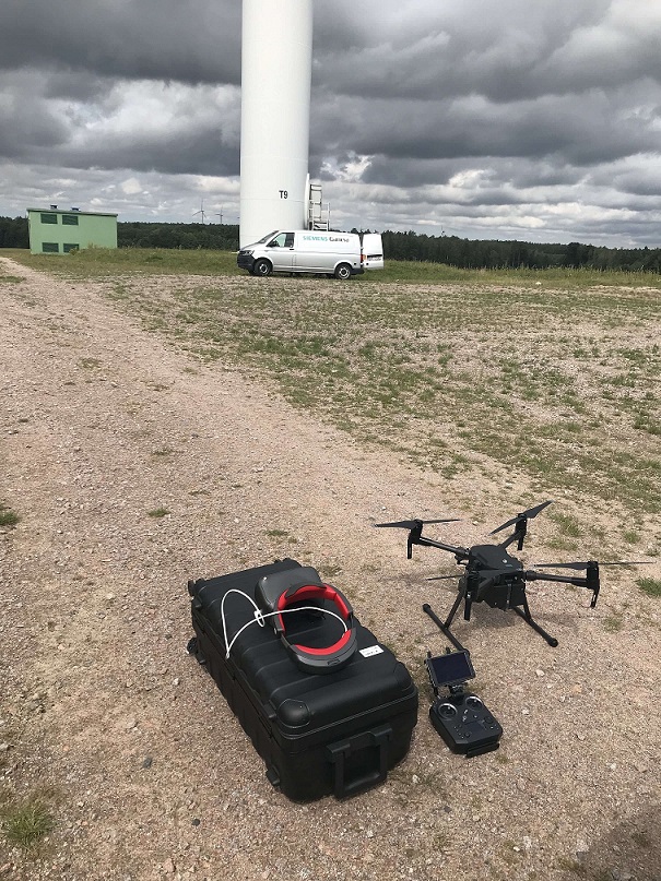 dron z aparaturą na tle turbiny