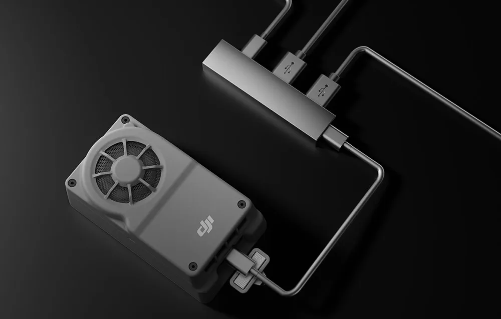 DJI onboard drone computer connected to a USB hub with three cables on a black background