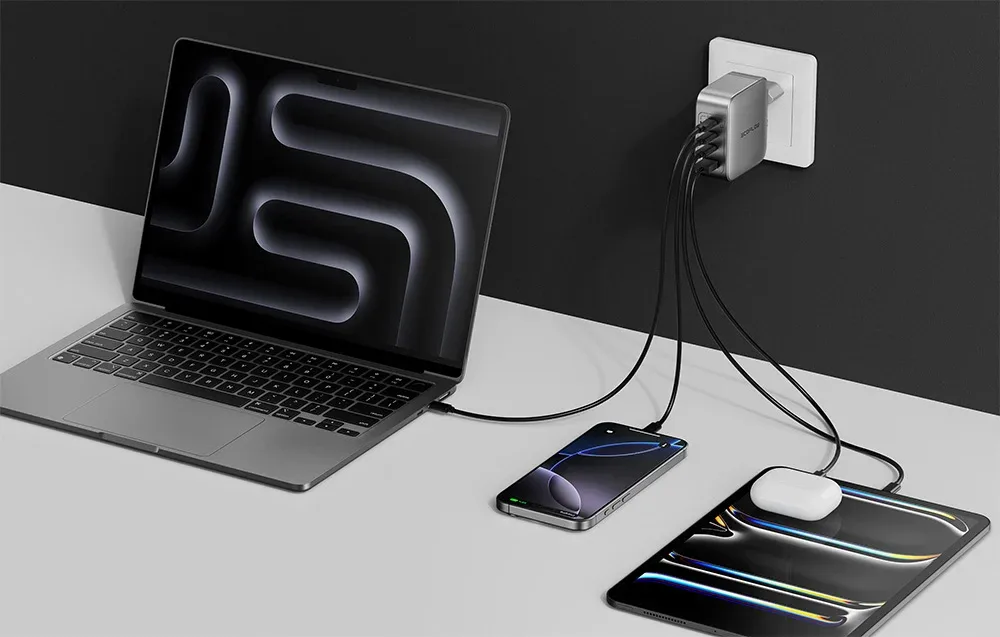 EcoFlow RAPID Pro charger plugged into a wall outlet and charging four devices including a laptop, phone, tablet, and TWS earbuds case