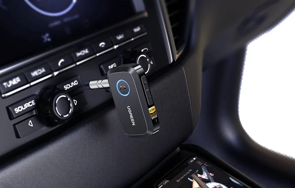 Czarny adapter Bluetooth UGREEN podłączony do radia samochodowego w kokpicie pojazdu