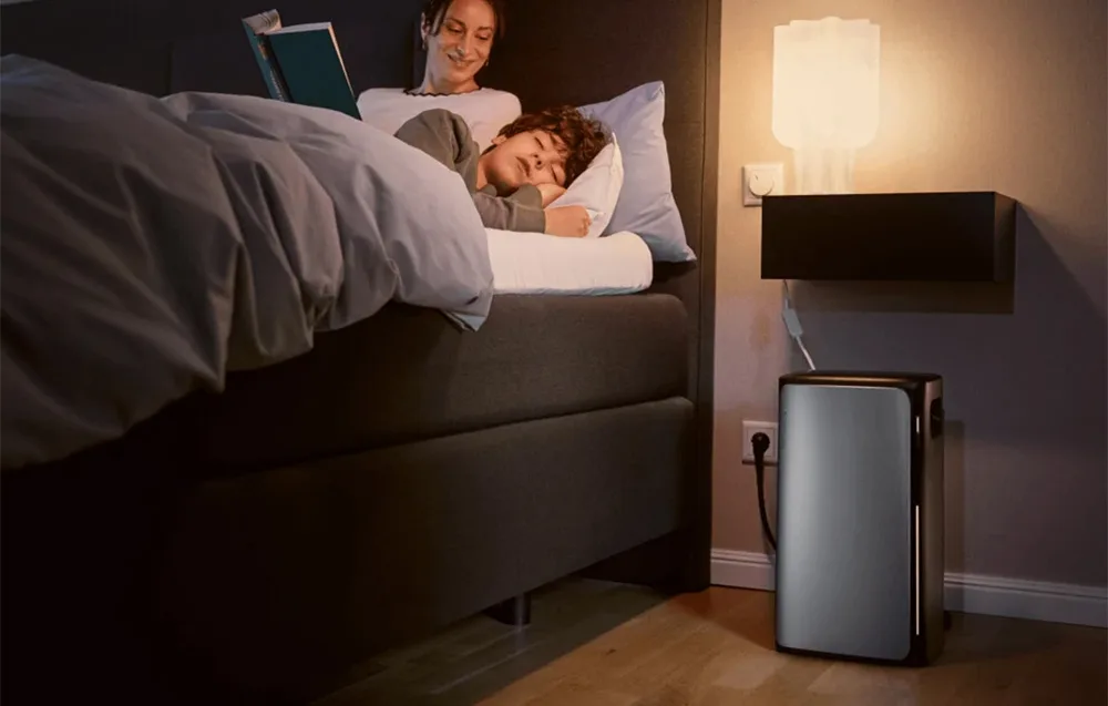 Couple in bed in a dark bedroom with the silver EcoFlow STREAM AC energy storage unit placed beside a power outlet