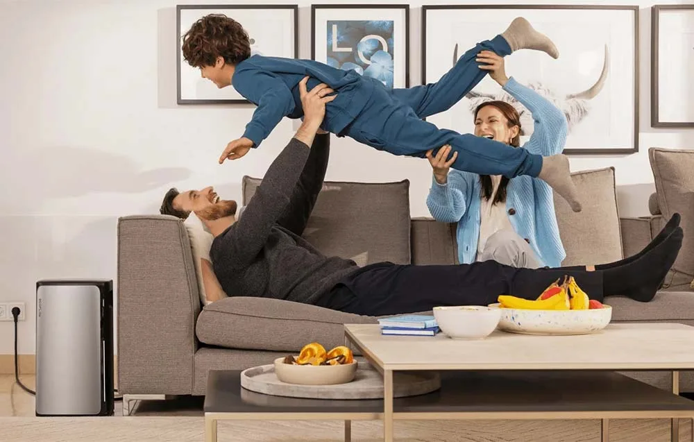 Family relaxing on a sofa in the living room next to the silver EcoFlow STREAM AC energy storage unit