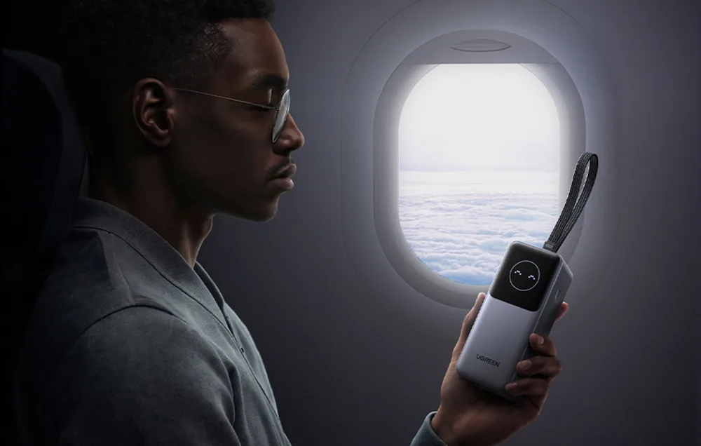 Man holding the Ugreen PB723 power bank near an airplane window