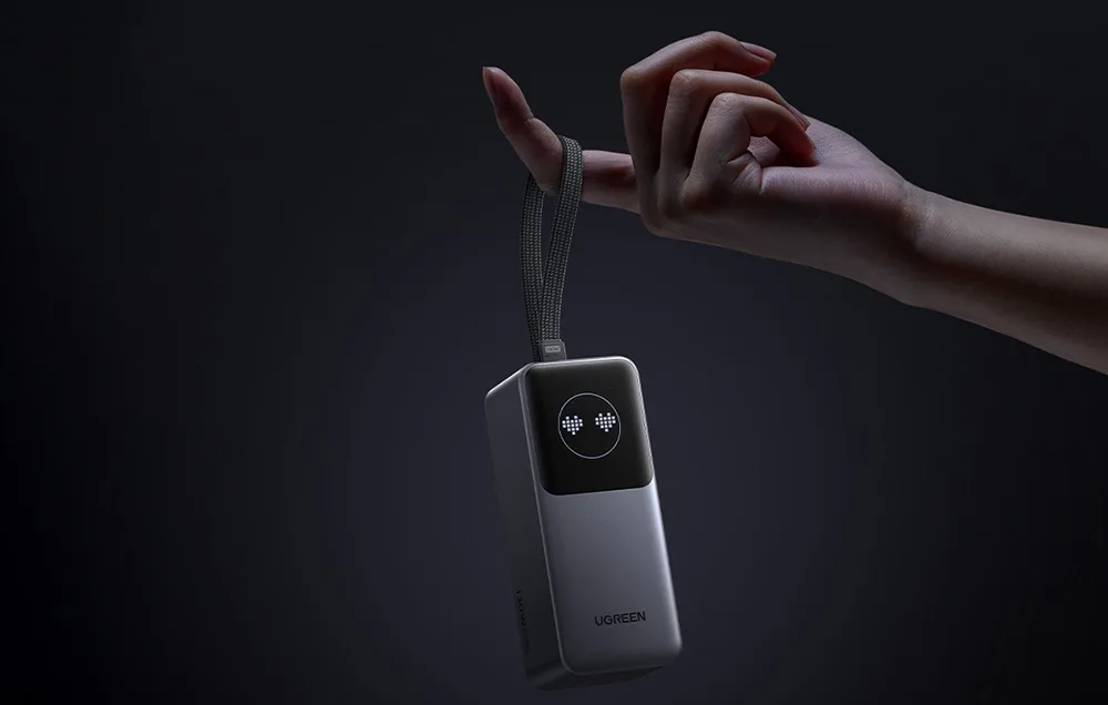 Ugreen PB723 power bank hanging from a finger with its carrying strap