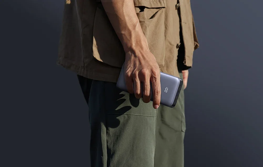 Man holding the Ugreen power bank outdoors against a dark background