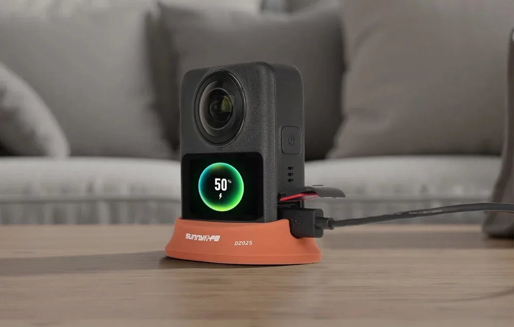 DJI Osmo 360 camera charging upright on an orange Sunnylife stand base on a wooden table
