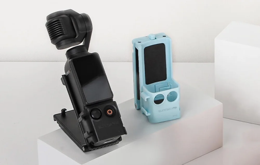 Kamera DJI Pocket zamontowana w uchwycie Sunnylife w kolorze czarnym obok pustego uchwytu w wersji niebieskiej