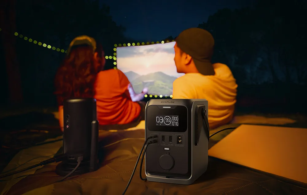 Two people watching a movie at night using a projector powered by the EcoFlow TRAIL 300 DC