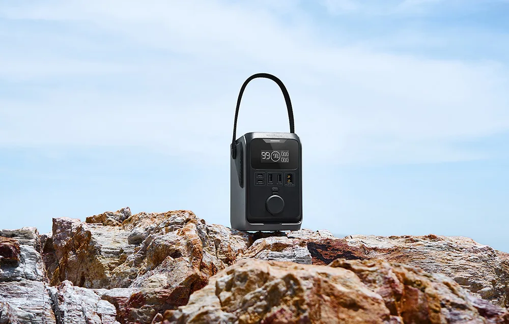 EcoFlow TRAIL 300 DC portable power station on a rock with blue sky and sea in the background