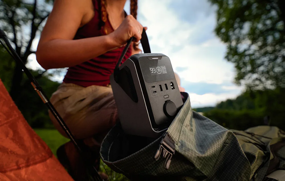 Woman placing the EcoFlow TRAIL 300 DC portable power station into a hiking backpack in the forest
