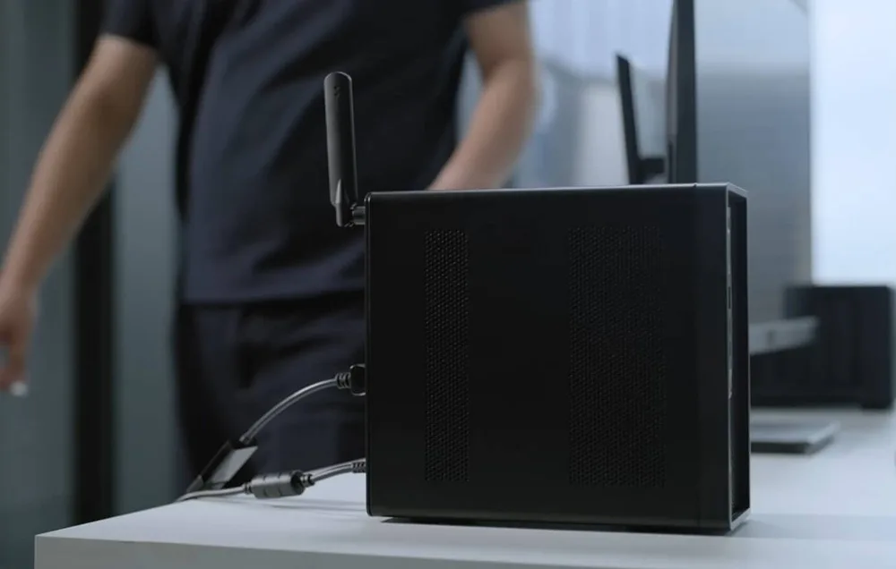 Tył czarnej obudowy komputera z antenami Wi-Fi i podłączonymi kablami na białym biurku