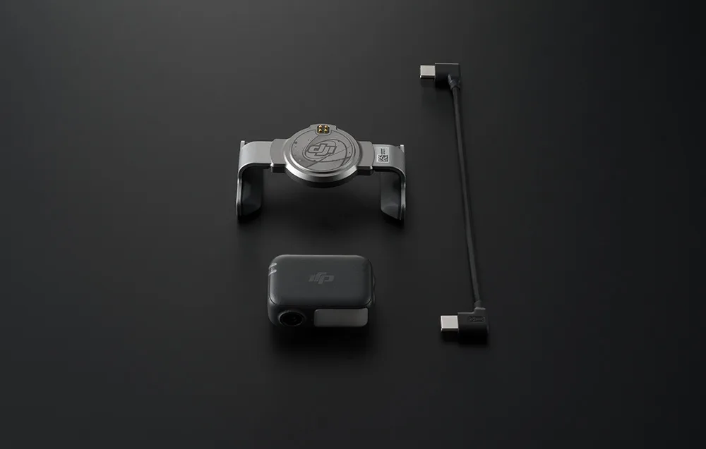 Zestaw DJI składający się z uchwytu, modułu bezprzewodowego i przewodu USB-C ułożony w rzędzie na czarnej powierzchni