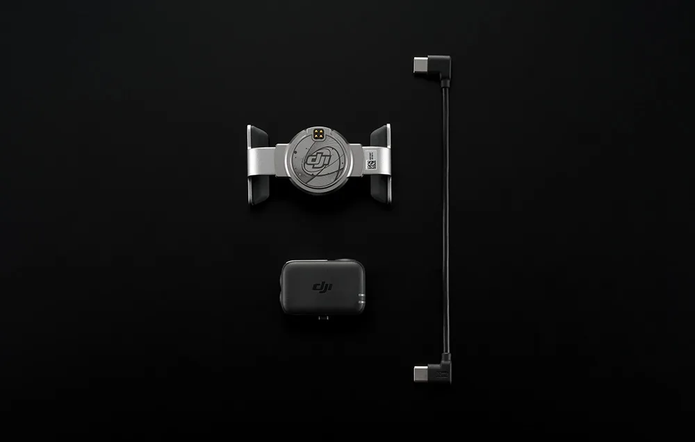 Widok z góry na uchwyt DJI, moduł bezprzewodowy i przewód USB-C ułożone równolegle na czarnym tle