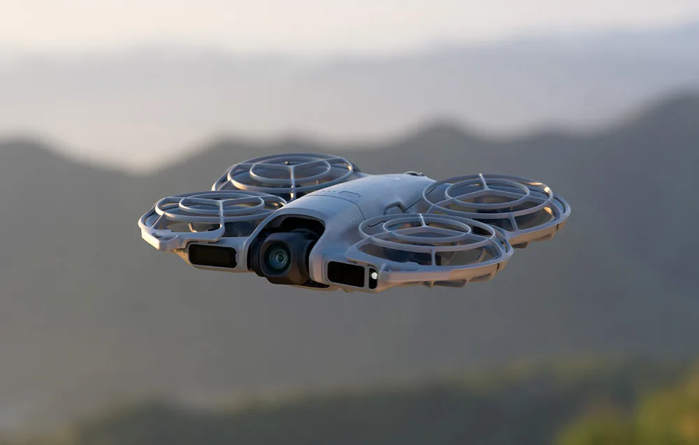 Дрон DJI Neo 2 із захистом пропелерів летить у повітрі на тлі гірського пейзажу