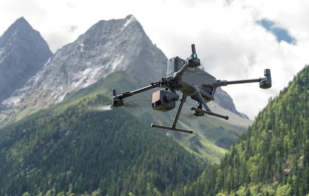 DJI drone with camera flying over conifer-covered mountains