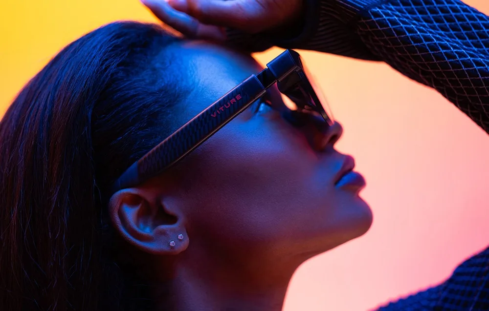 Close-up of a woman wearing VITURE XR Luma glasses against a colorful gradient background