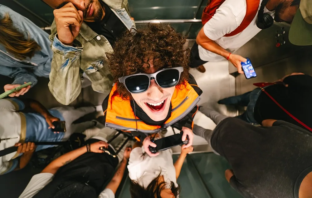 Smiling man wearing VITURE XR Luma glasses in a crowded elevator