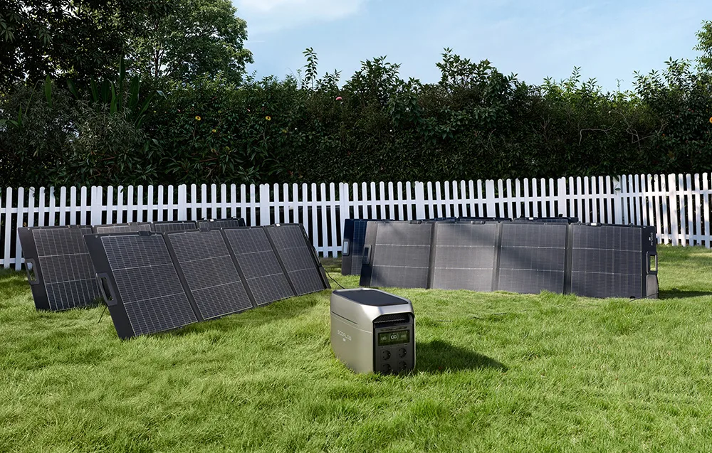 EcoFlow power station on a garden lawn with foldable solar panels near a white fence.