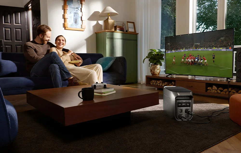 A couple watching a football match in the living room with the EcoFlow power station connected to the TV.