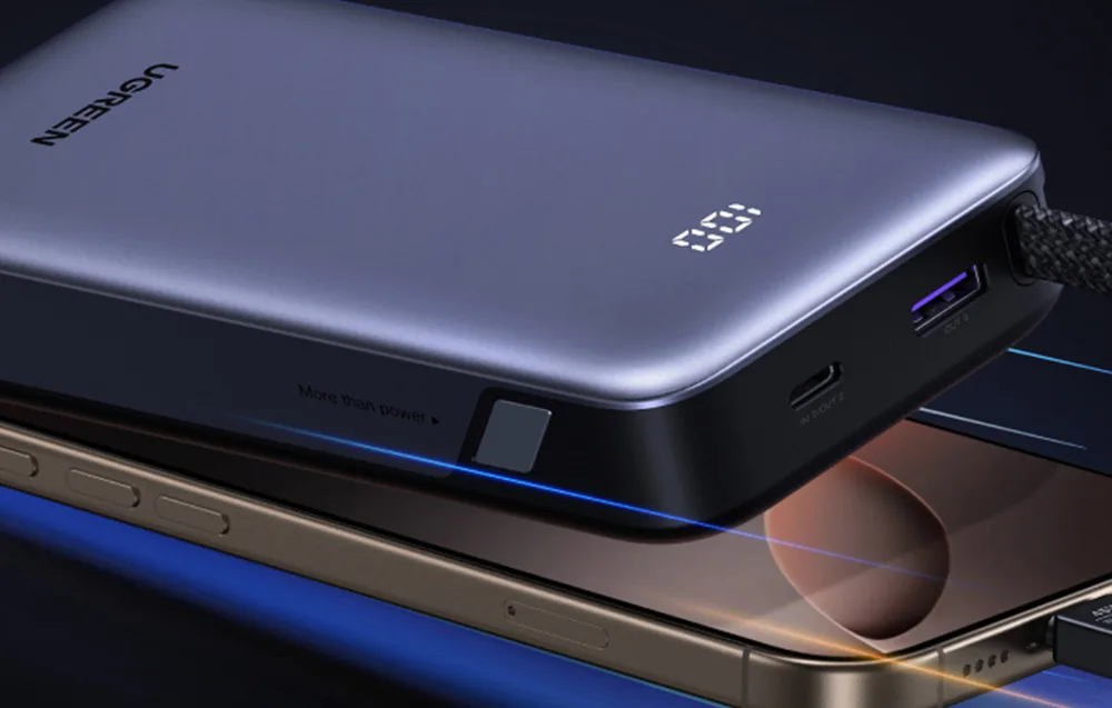 Gray UGREEN power bank placed next to a smartphone.