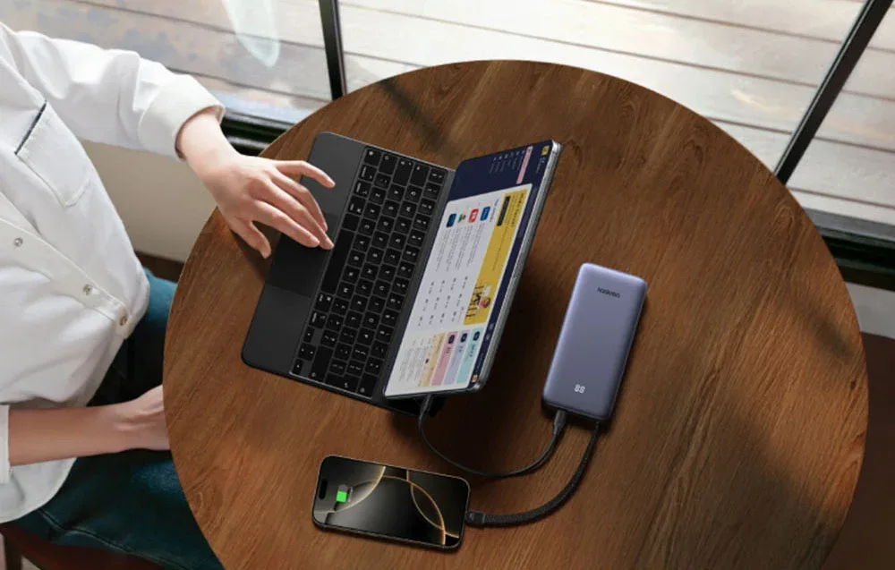 UGREEN power bank with built-in cable connected to a laptop and smartphone.