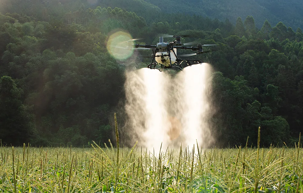 Dron DJI Agras T100 opryskujący pole