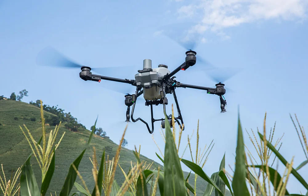 Dron rolniczy DJI Agras T25P w locie nad polem na tle nieba