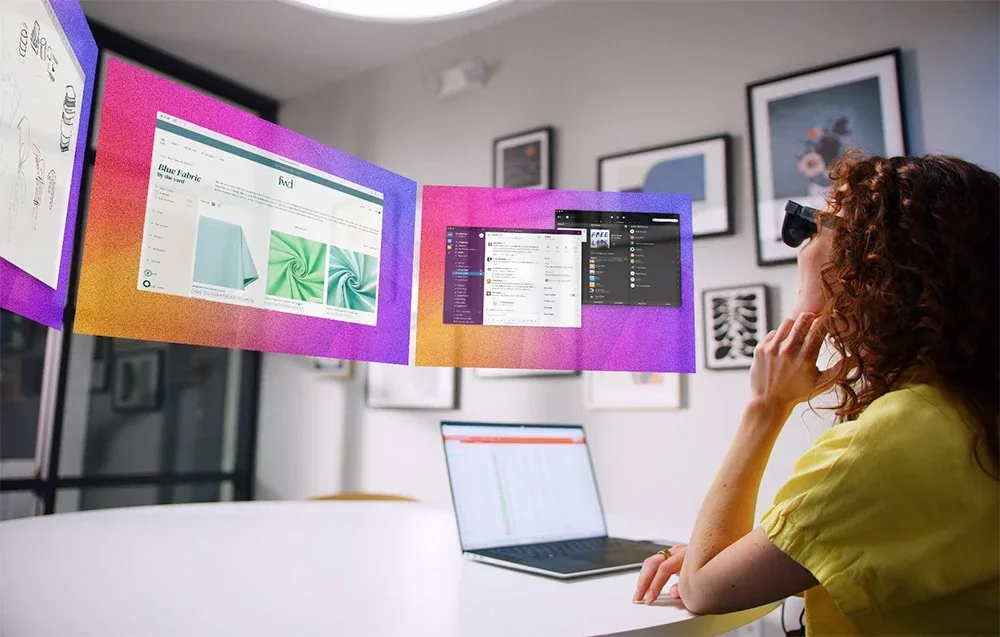 Woman wearing VITURE XR Luma Pro glasses working at a desk with a laptop and virtual floating screens