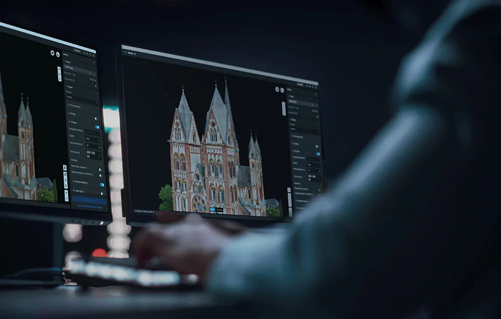 osoba w ciemnym pomieszczeniu pracująca przy monitorach z wyświetlonym oprogramowaniem do tworzenia modeli 3D i map 2D
