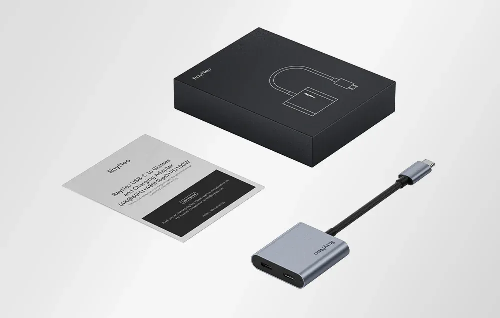 Adapter RayNeo USB-C z kablem i instrukcją obok opakowania, przedstawiony na jasnym tle.