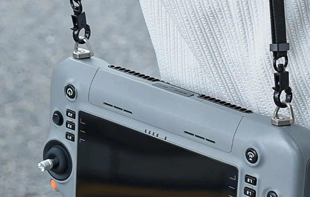 Drone controller hanging on a neck strap with metal mounting hooks