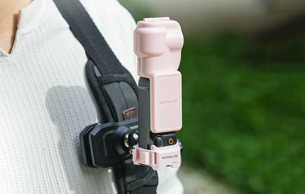 Камера DJI Osmo Pocket 3 з рожевим кріпленням Sunnylife BK03, закріплена на ремені рюкзака