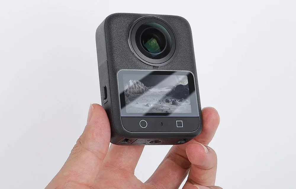 Компактна камера DJI Osmo 360 у руці користувача із сенсорним екраном та встановленим захистом