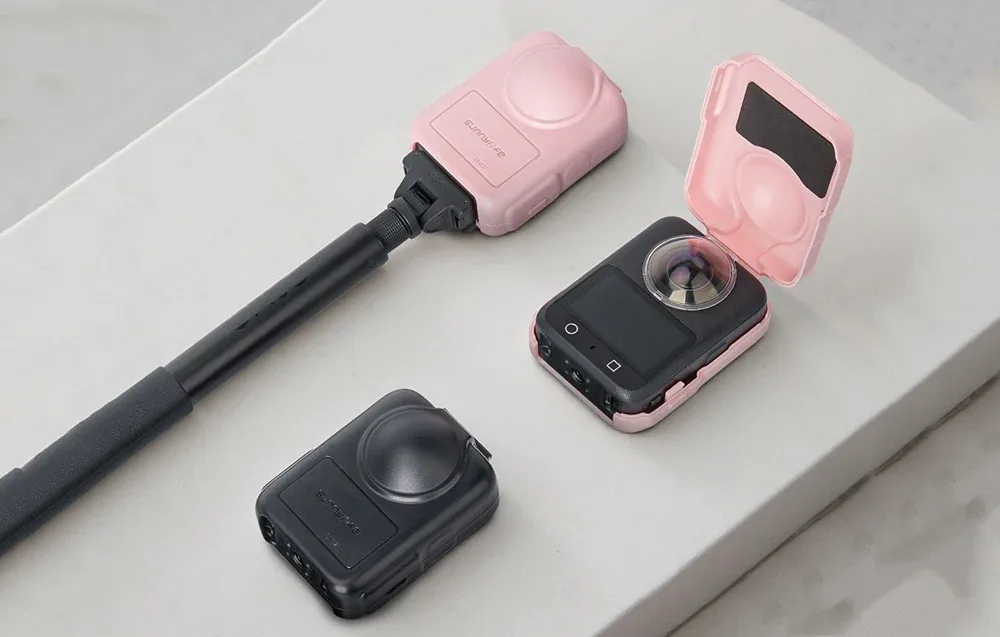 Three DJI Osmo 360 cameras in protective cases with a selfie stick on a bright surface.
