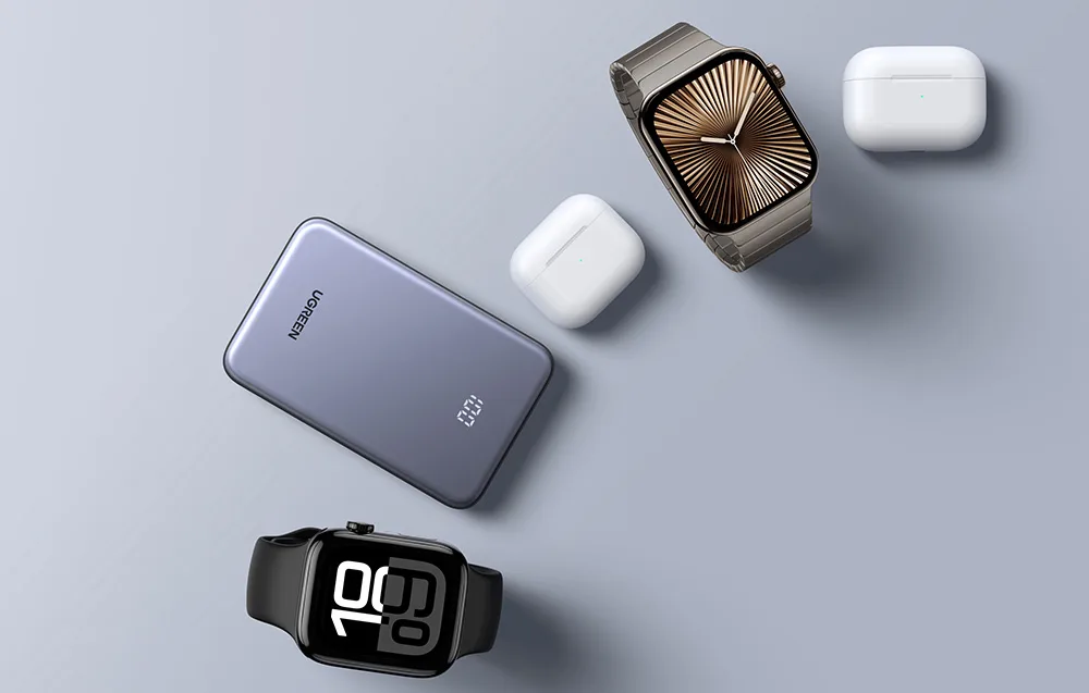 Powerbank Ugreen obok smartwatchy i słuchawek TWS na szarym tle
