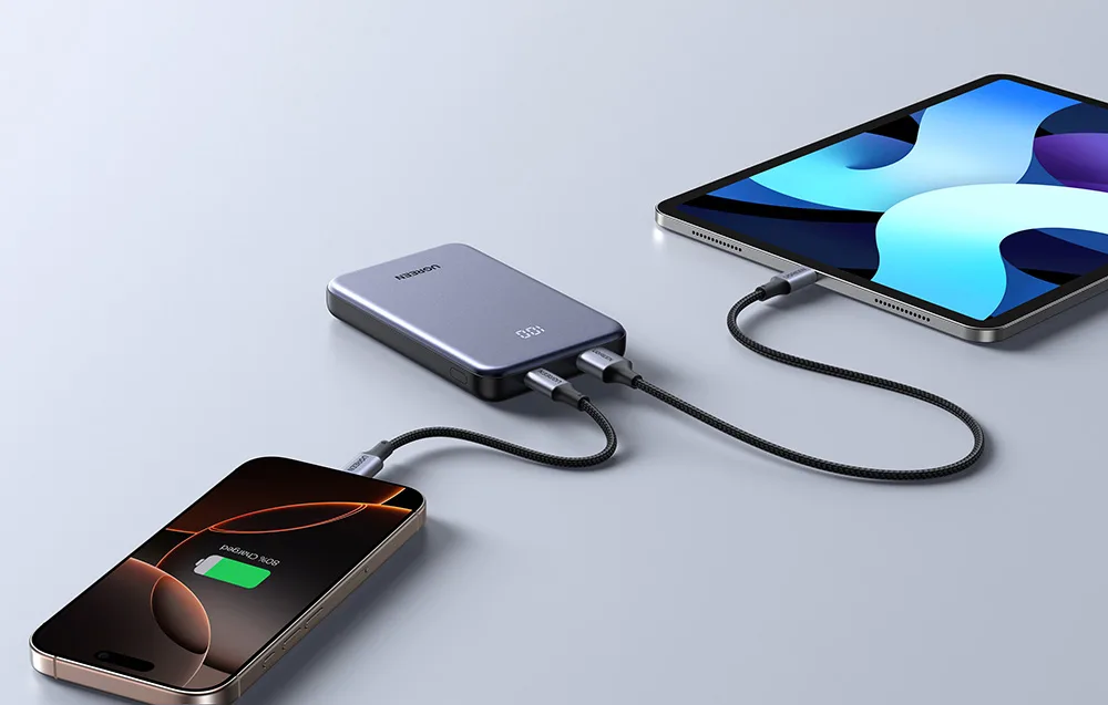 Szary powerbank Ugreen na stole podłączony do laptopa i tabletu