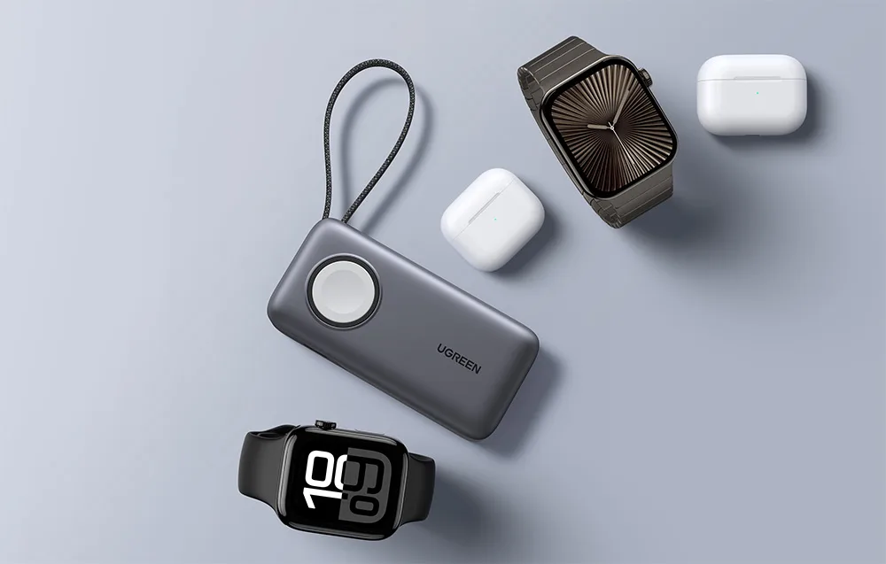 Gray UGREEN power bank placed next to smartwatches and TWS earbuds