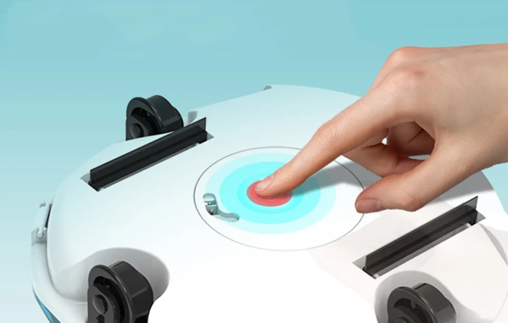 Hand pressing a red button on a white pool robot with turquoise lighting on a light blue background