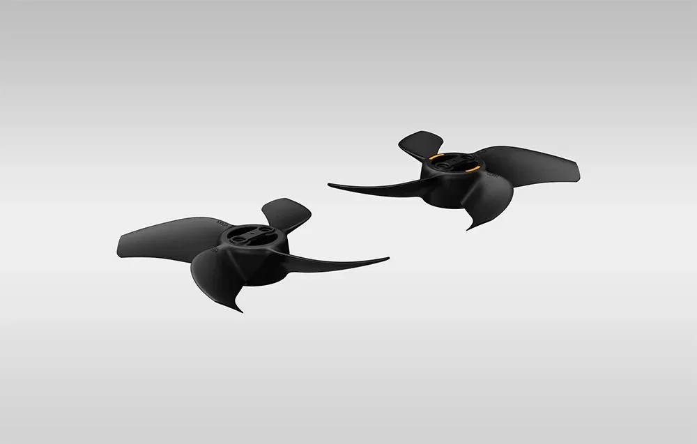 Two pairs of black three-blade propellers for DJI Avata 360 with orange mounting accents on a plain gray background