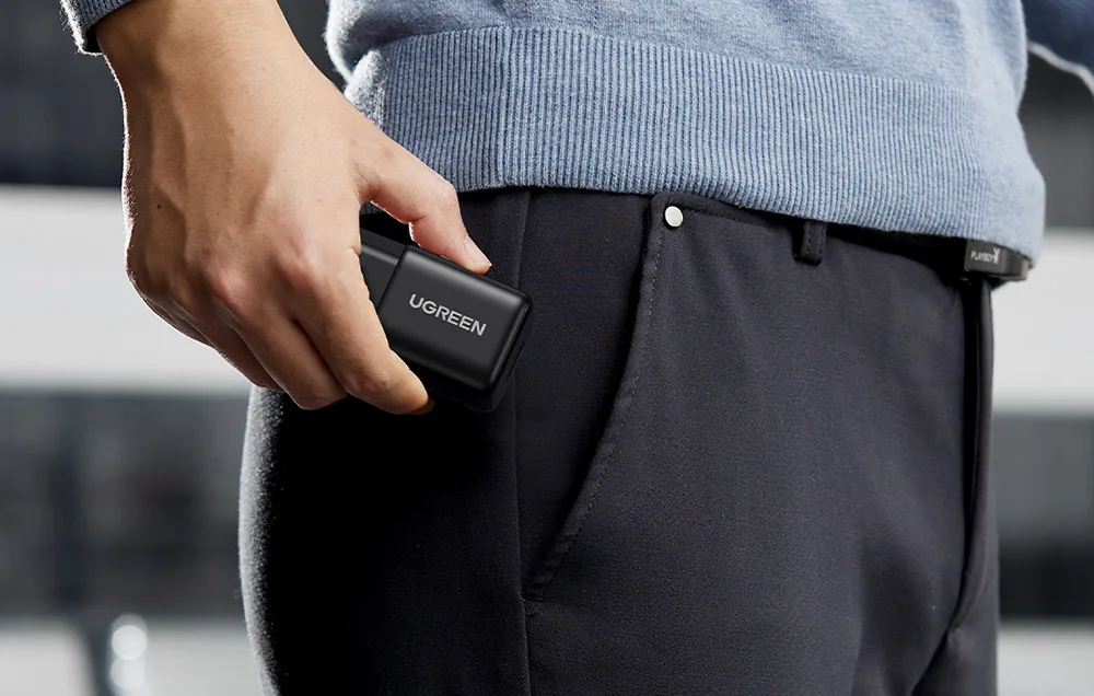 Person placing the compact Ugreen X518 charger into a pocket