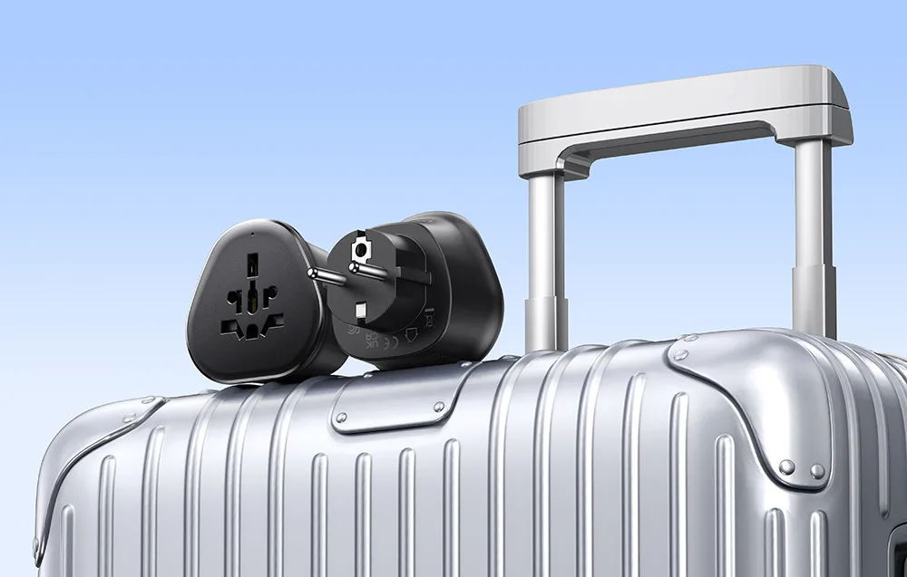 UGREEN S500 universal travel adapter placed on a travel suitcase.