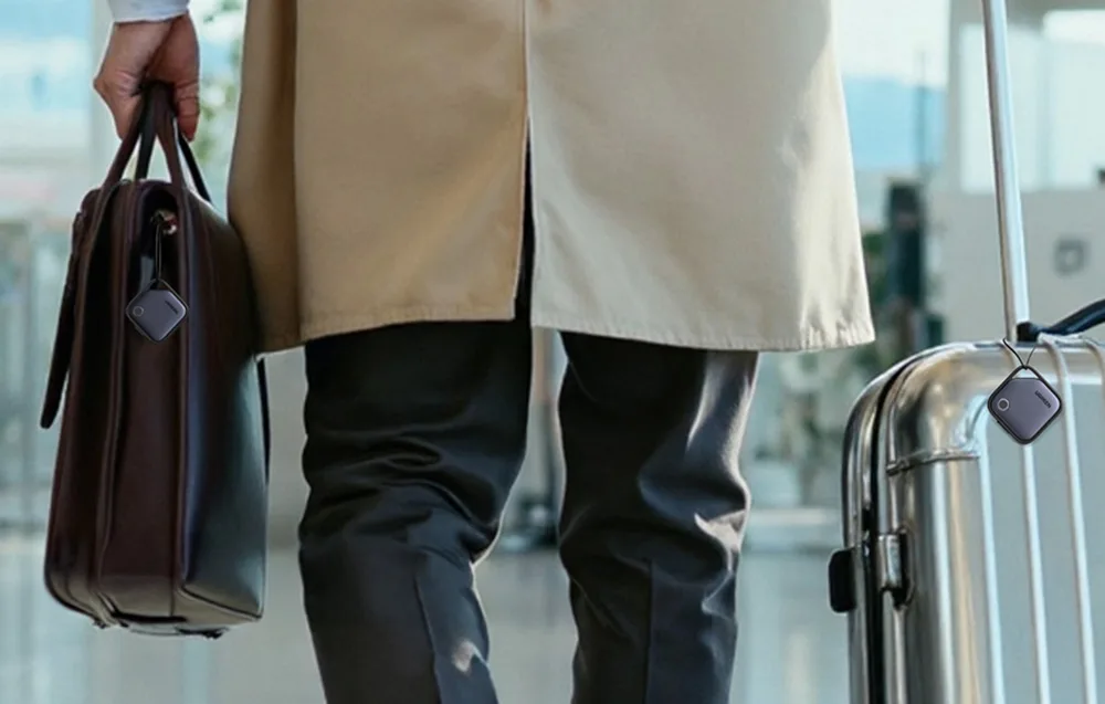 A person walking with a bag and suitcase equipped with UGREEN smart trackers.