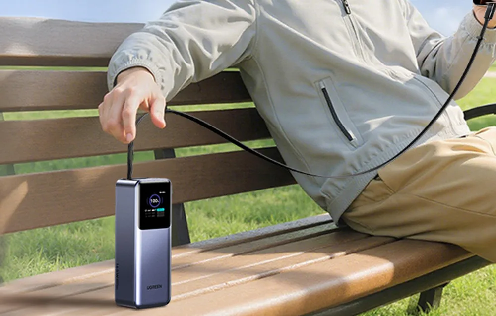 Ugreen PB726 power bank charging a smartphone outdoors on a park bench