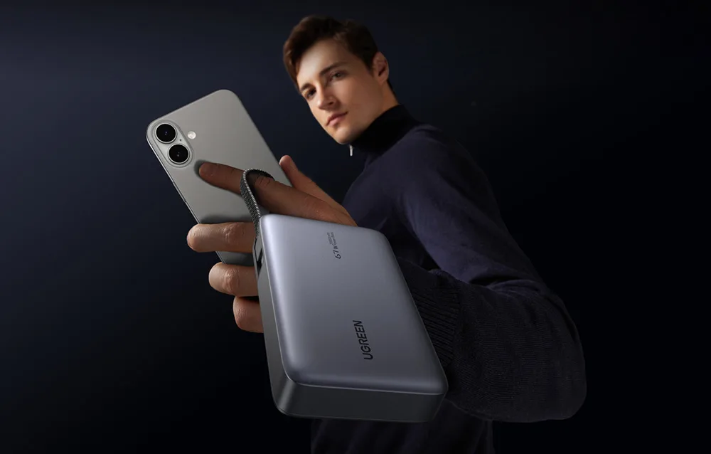Man holding the Ugreen PB550 power bank and smartphone in one hand to show its portable size.