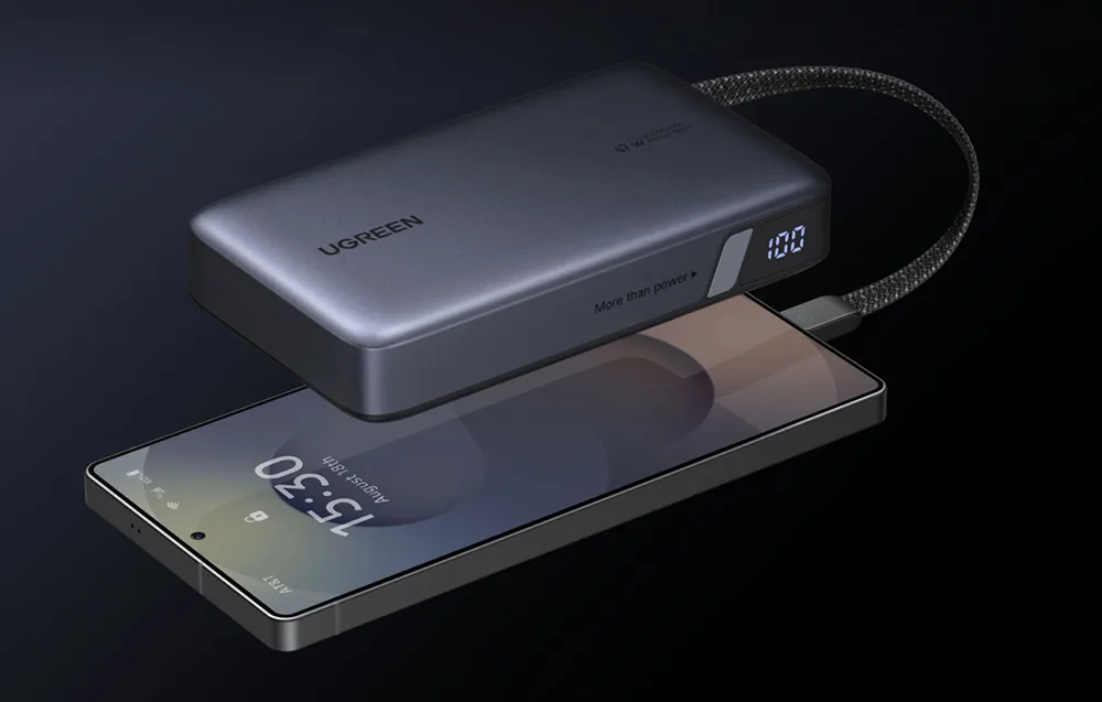 Close-up of the Ugreen 67W power bank charging a smartphone with bright battery level display on the side.
