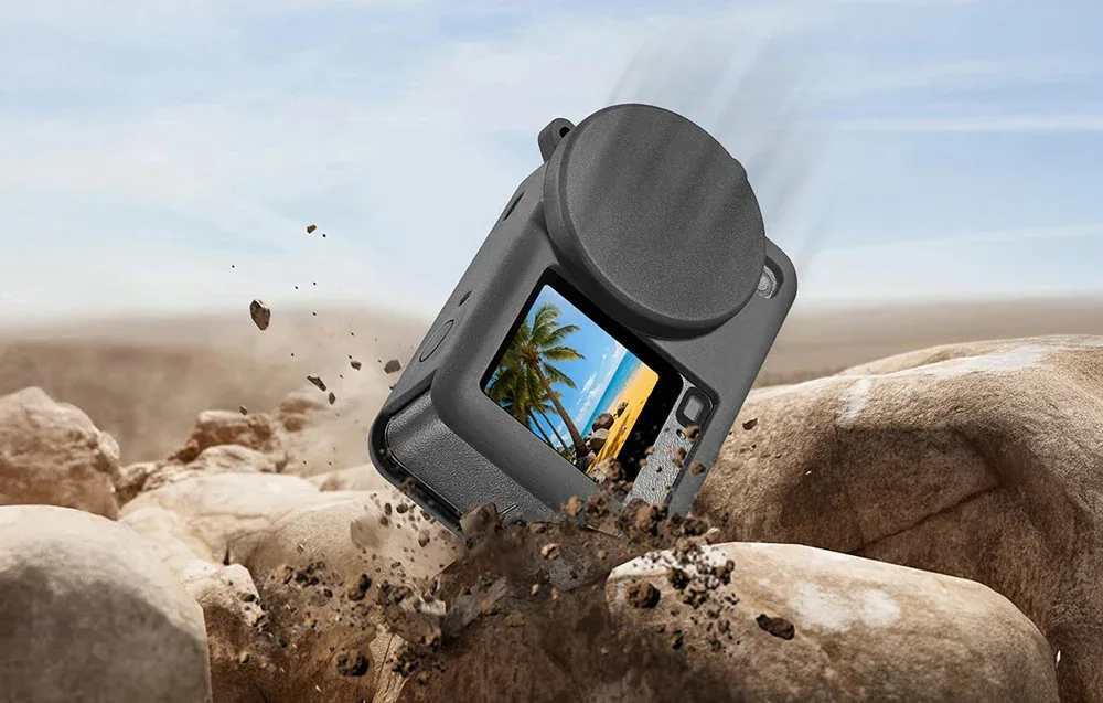 DJI Osmo Action 6 in a silicone case with lens cover falling onto rocks in an outdoor setting