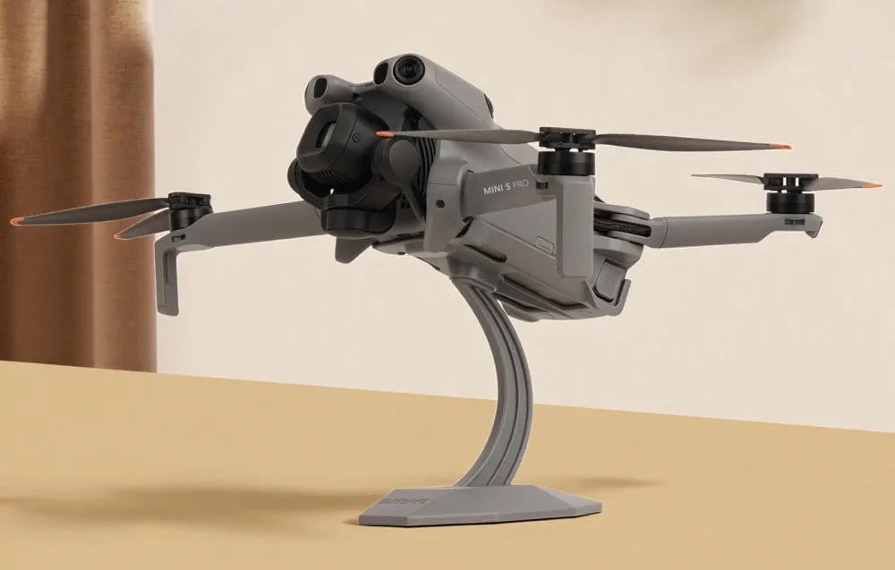 Dron DJI Mini 5 Pro ustawiony na stojaku na blacie w jasnym pomieszczeniu