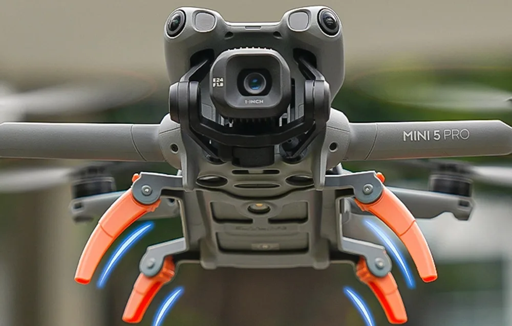 Widok od spodu na drona DJI Mini 5 Pro z zamontowanymi pomarańczowymi wysuwanymi nóżkami do lądowania