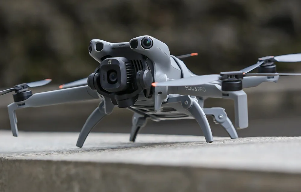 Dron DJI Mini 5 Pro stojący na betonowej powierzchni z rozłożonymi nogami do lądowania