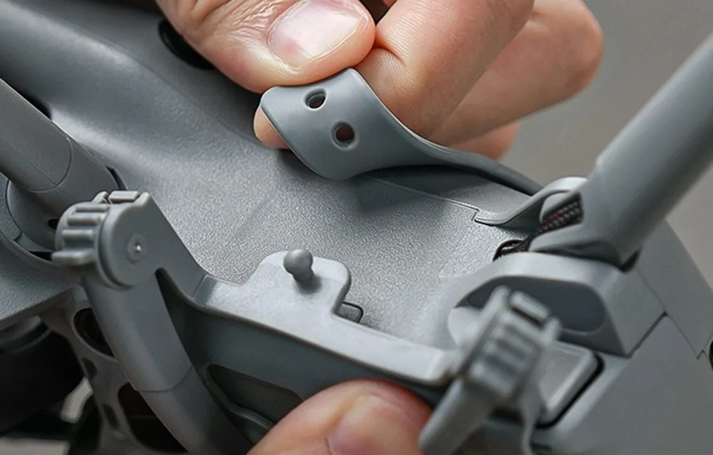 Zbliżenie na ręce zakładające gumowy pasek zabezpieczający na dronie DJI Mini 5 Pro